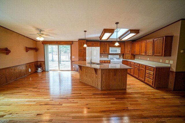 N7957 15th Ave, New Lisbon, WI 53950 - kitchen with white appliances, light wood-style floors, brown cabinetry, wainscoting, and lofted ceiling