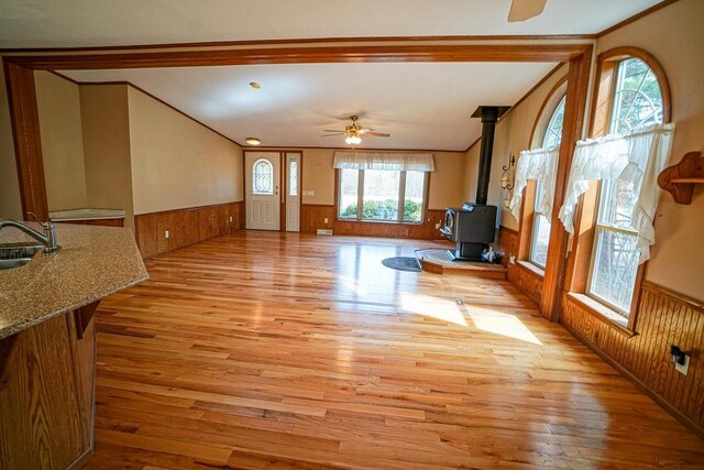 N7957 15th Ave, New Lisbon, WI 53950 - unfurnished living room featuring a sink, a wood stove, a ceiling fan, and wainscoting