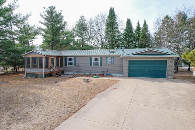 N7957 15th Ave, New Lisbon, WI 53950 - view of front of home with metal roof, a garage, concrete driveway, and a sunroom