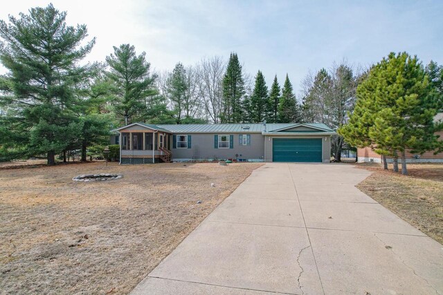 N7957 15th Ave, New Lisbon, WI 53950 - view of front of property featuring driveway, metal roof, a garage, and a sunroom