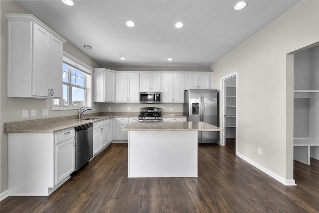 kitchen with dark wood-style floors, appliances with stainless steel finishes, white cabinetry, and a sink
