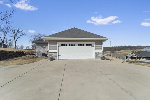 301 Church St, Barneveld, WI 53507 - view of property exterior with stone siding, cooling unit, concrete driveway, and roof with shingles