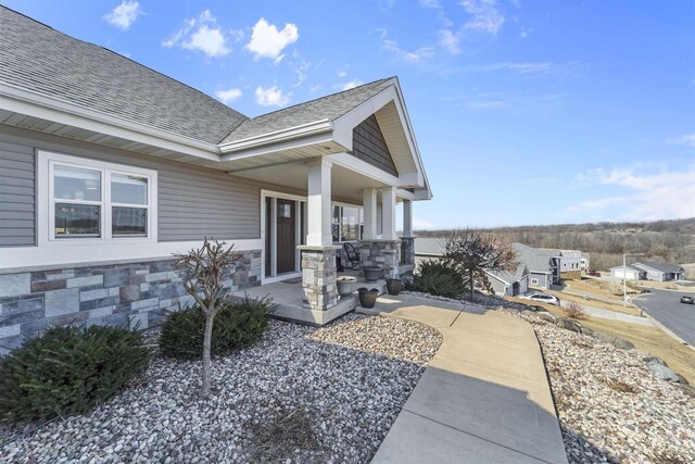 301 Church St, Barneveld, WI 53507 - doorway to property with stone siding, covered porch, and roof with shingles