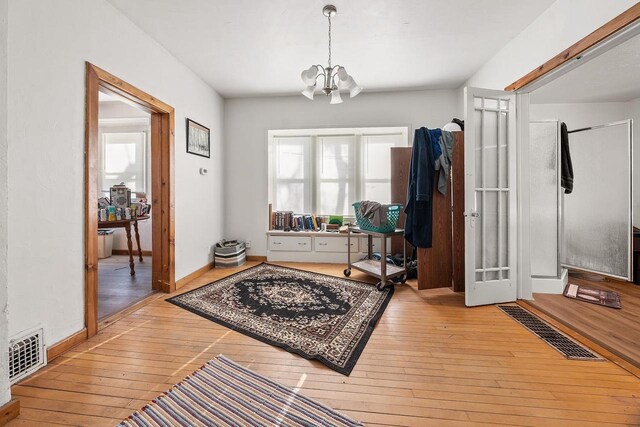 interior space featuring hardwood / wood-style flooring, a notable chandelier, baseboards, and visible vents