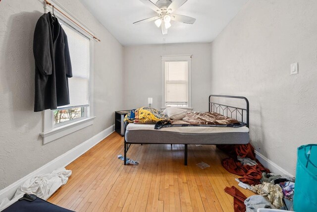 bedroom featuring light wood-style flooring, multiple windows, baseboards, and ceiling fan