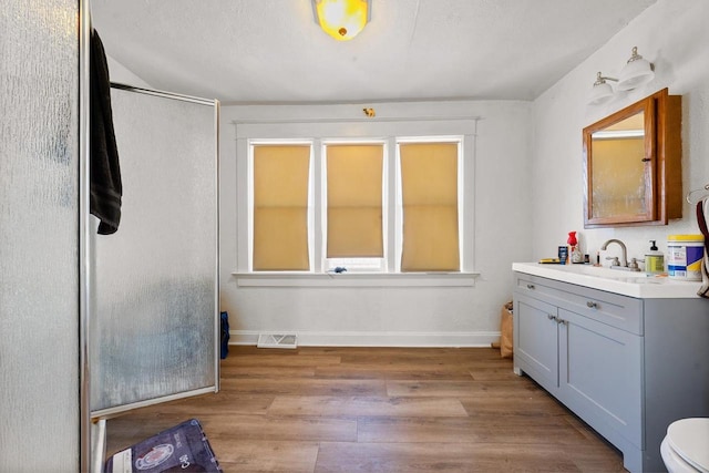 bathroom with visible vents, toilet, wood finished floors, baseboards, and vanity
