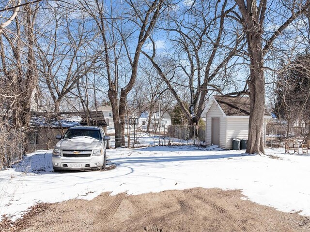yard covered in snow featuring a storage unit, a garage, an outdoor structure, and fence