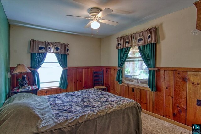 9293 N County Hwy E, Hayward, WI 54843 - carpeted bedroom with wainscoting, a ceiling fan, wood walls, and multiple windows