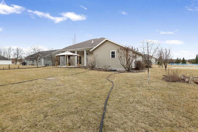 back of property featuring a gazebo and a yard
