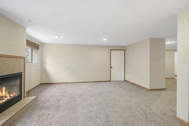 unfurnished living room with recessed lighting, carpet, baseboards, and a tile fireplace