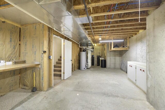 unfinished below grade area featuring gas water heater and stairs