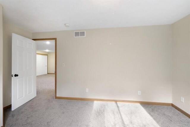 carpeted spare room with visible vents and baseboards