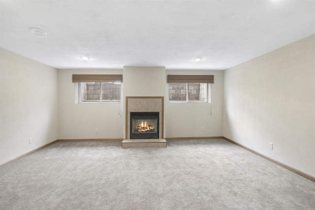 unfurnished living room with a wealth of natural light, carpet flooring, a fireplace, and baseboards