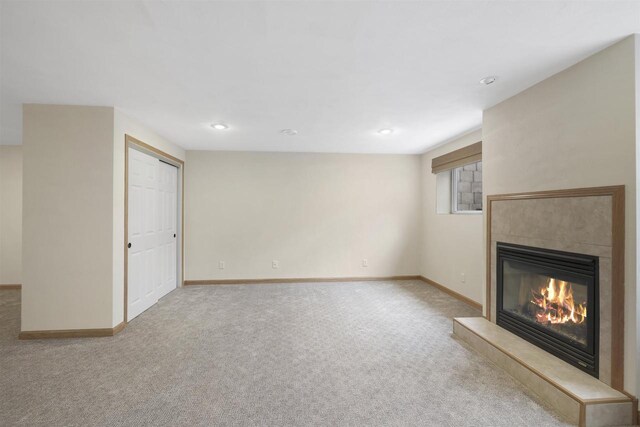 unfurnished living room featuring carpet, baseboards, and a tile fireplace