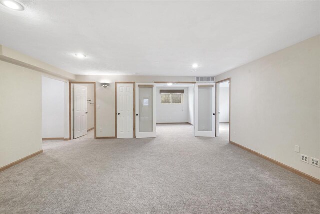 empty room featuring baseboards, visible vents, and light carpet