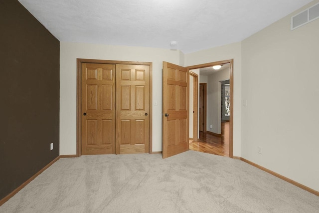 unfurnished bedroom featuring visible vents, baseboards, carpet, and a closet