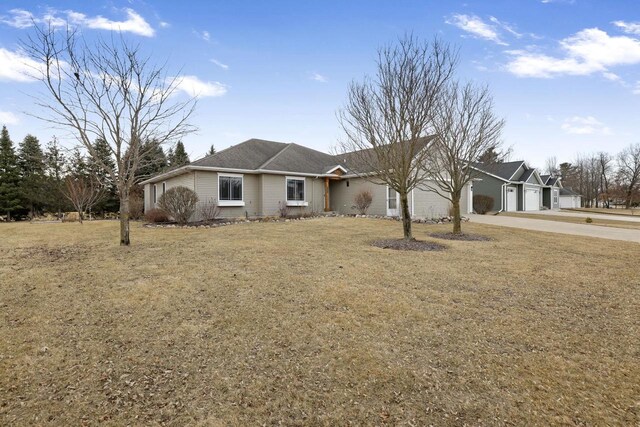 ranch-style home featuring concrete driveway, an attached garage, and a front lawn