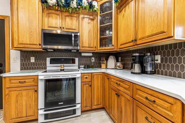 1300 Jack Oak Rd, Cassville, WI 53806 - kitchen with stainless steel microwave, brown cabinets, light countertops, and electric range