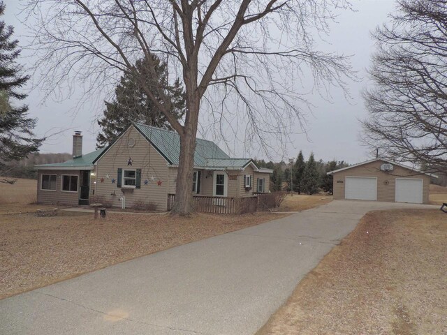 view of front of property with an outdoor structure, metal roof, a detached garage, and a chimney