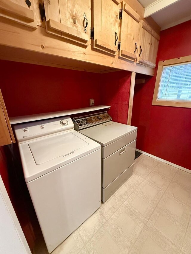 clothes washing area with cabinet space, light floors, and washer and dryer