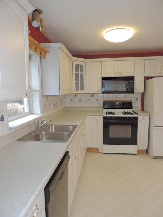 kitchen featuring freestanding refrigerator, a sink, dishwasher, black microwave, and range with gas cooktop