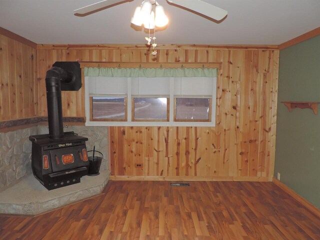unfurnished living room with wooden walls, wood finished floors, and ceiling fan