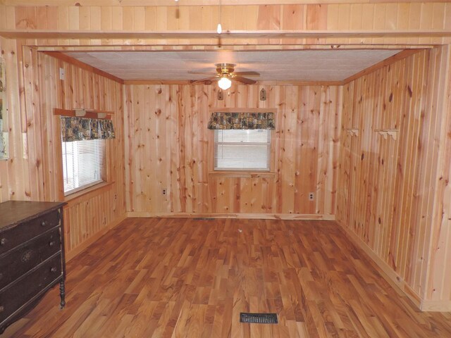 spare room featuring ceiling fan, baseboards, wooden walls, and wood finished floors