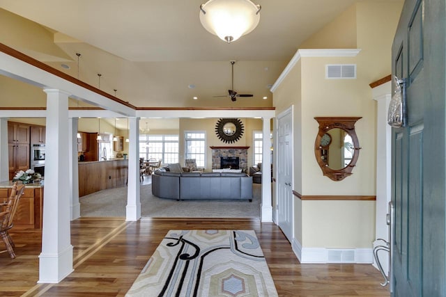 N4795 County Road V, Poynette, WI 53955 - foyer featuring a stone fireplace, visible vents, ornate columns, ceiling fan, and wood finished floors
