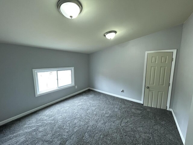 6082 N 36th St, Milwaukee, WI 53209 - unfurnished room featuring baseboards, dark colored carpet, and lofted ceiling