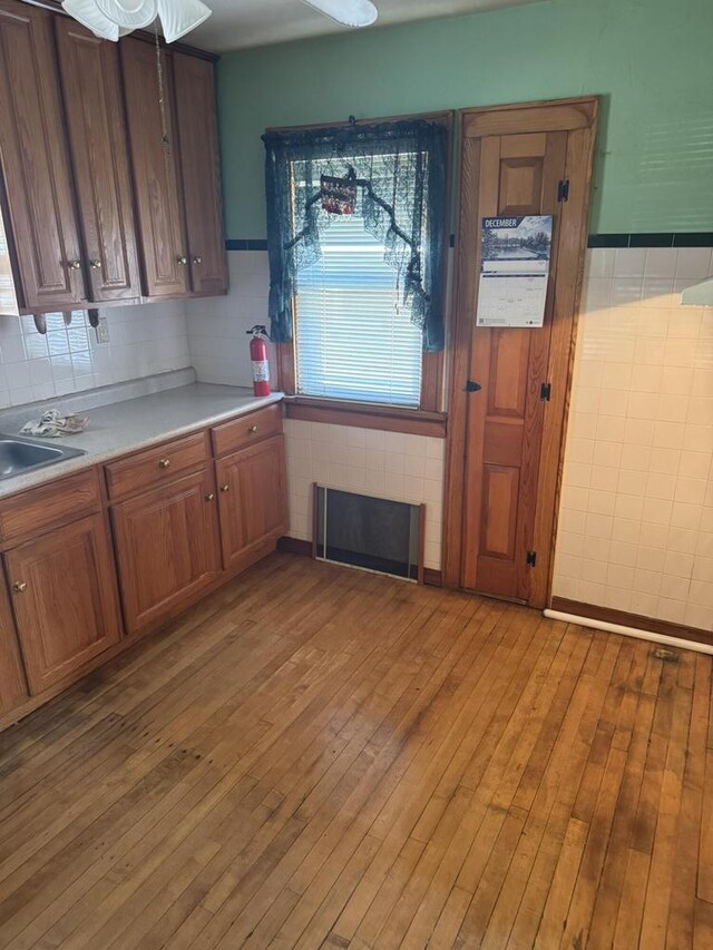 7126 W Congress St, Milwaukee, WI 53218 - kitchen with brown cabinets, tile walls, light wood-style flooring, and light countertops