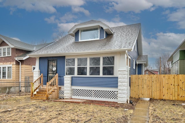 bungalow-style home featuring roof with shingles, entry steps, and fence