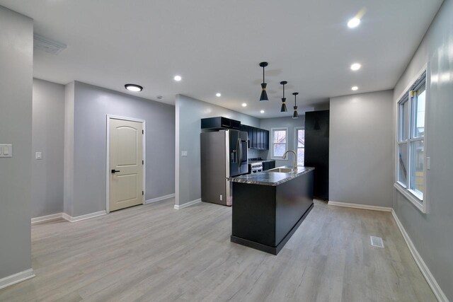 kitchen featuring an island with sink, light wood-style flooring, visible vents, a sink, and stainless steel appliances
