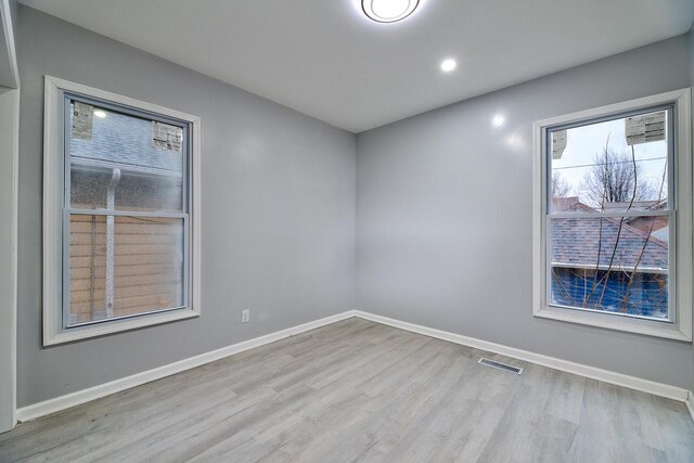 spare room with wood finished floors, baseboards, and visible vents