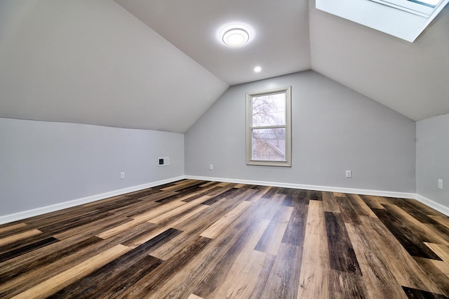 additional living space with vaulted ceiling with skylight, visible vents, baseboards, and dark wood-style floors
