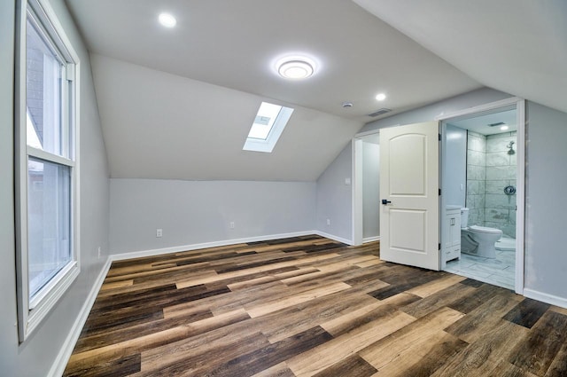additional living space with dark wood-type flooring, visible vents, baseboards, and lofted ceiling with skylight