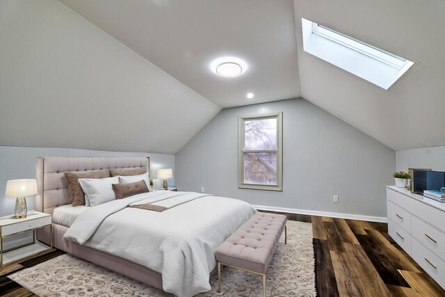 bedroom with vaulted ceiling with skylight, baseboards, and dark wood finished floors