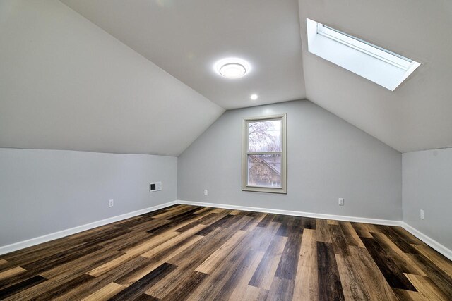 additional living space with visible vents, baseboards, vaulted ceiling with skylight, and dark wood-style floors