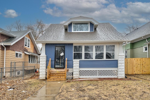bungalow with entry steps, fence, and a shingled roof