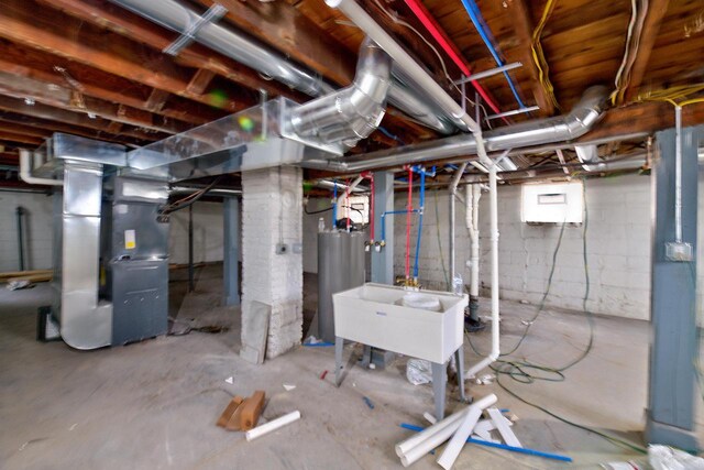 unfinished basement featuring a sink, gas water heater, and heating unit