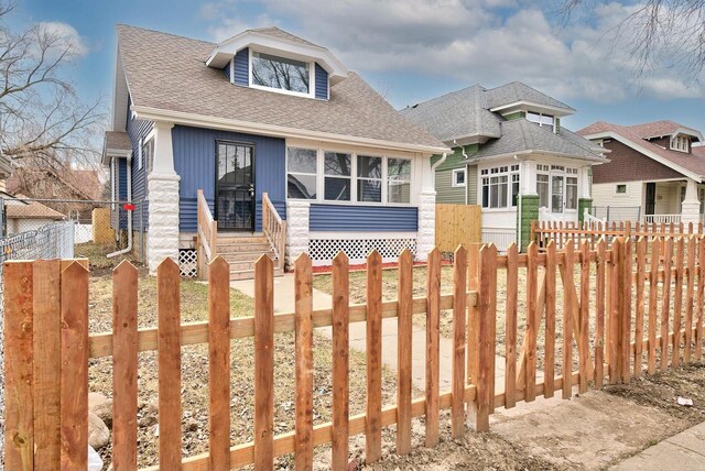 view of front of property with roof with shingles and a fenced front yard