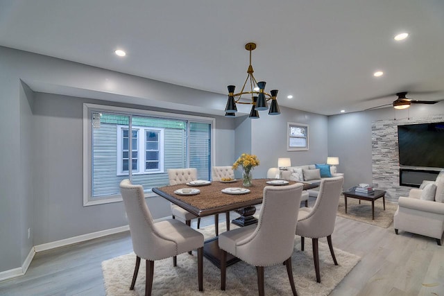 dining room with baseboards, light wood-type flooring, recessed lighting, and a fireplace