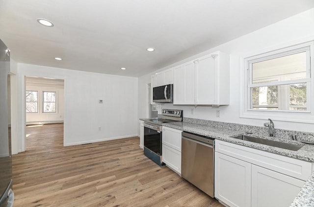 kitchen featuring white cabinetry, stainless steel appliances, light wood-type flooring, and a sink