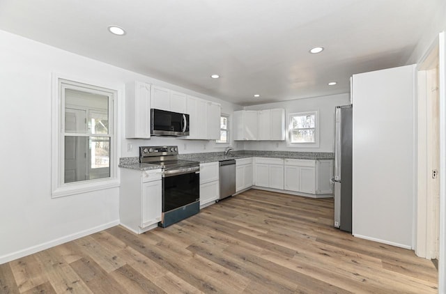 kitchen with light wood-type flooring, white cabinetry, recessed lighting, stainless steel appliances, and baseboards