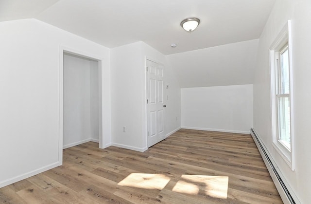 bonus room featuring a baseboard heating unit, vaulted ceiling, wood finished floors, and a healthy amount of sunlight