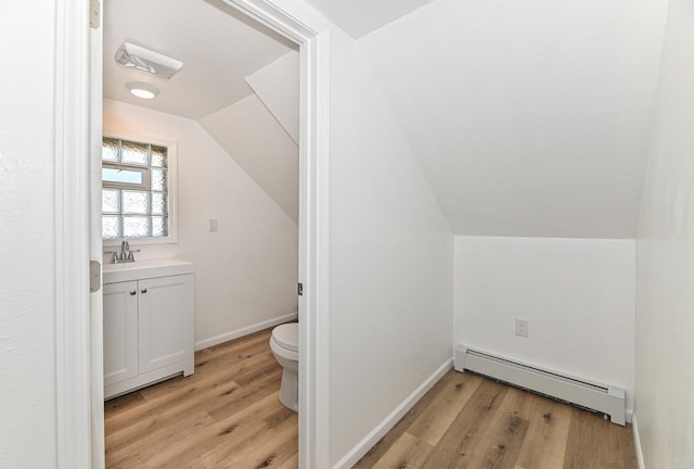 bathroom with a baseboard heating unit, lofted ceiling, toilet, and wood finished floors