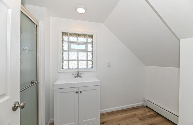 bathroom featuring wood finished floors, baseboards, vaulted ceiling, baseboard heating, and a shower with door