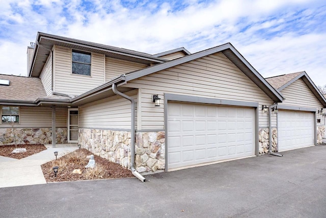 N761 Waubunsee Trl Unit 2, Fort Atkinson, WI 53538 - view of front of house featuring a garage, driveway, stone siding, and a shingled roof