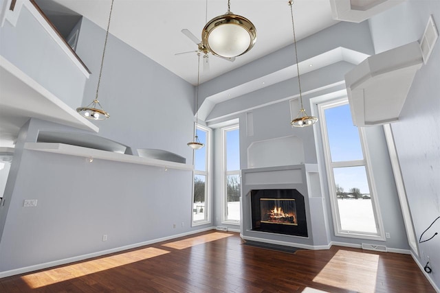 2155 Cottonwood Dr, Menasha, WI 54952 - unfurnished living room featuring a glass covered fireplace, ceiling fan, a towering ceiling, and hardwood / wood-style flooring