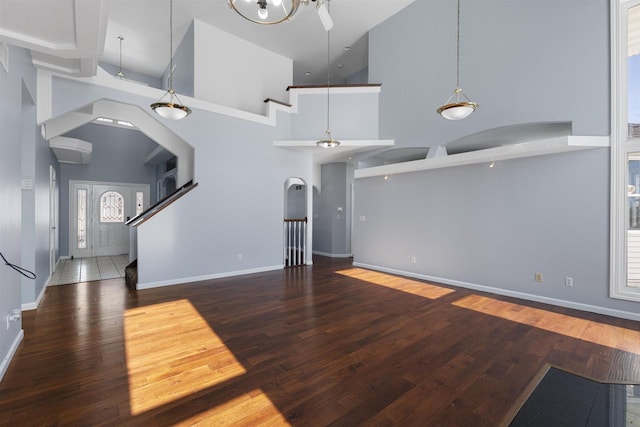 2155 Cottonwood Dr, Menasha, WI 54952 - unfurnished living room featuring baseboards, arched walkways, wood-type flooring, and a towering ceiling