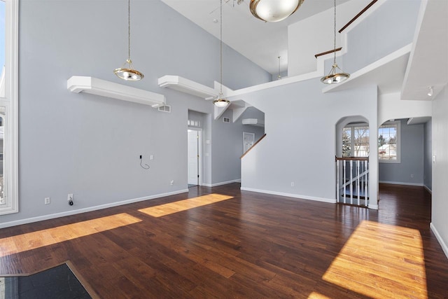 2155 Cottonwood Dr, Menasha, WI 54952 - living room featuring arched walkways, a towering ceiling, baseboards, and wood-type flooring
